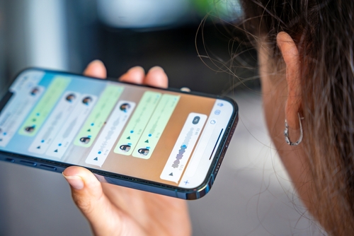 Prague, Czech republic - May 2, 2024: Woman holding iPhone with chat application WhatsApp on the screen, using mobile application for voice messaging at home. High quality photo
