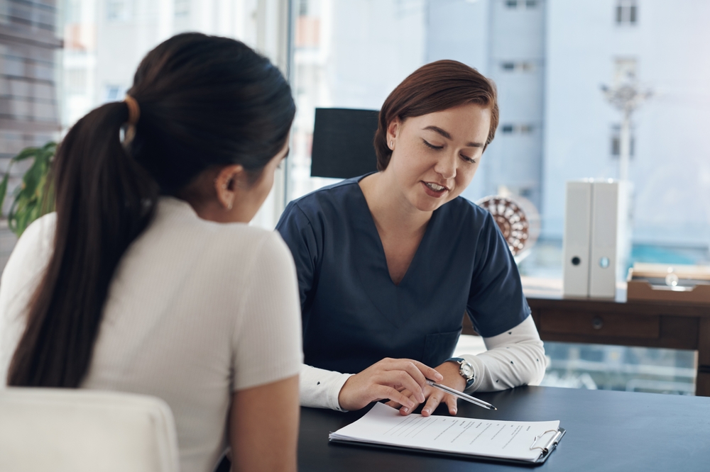 Nurse, woman and clipboard or patient for healthcare with discussion, medical history and checklist in hospital office. Consultation, expert and questions for health insurance, treatment and checkup