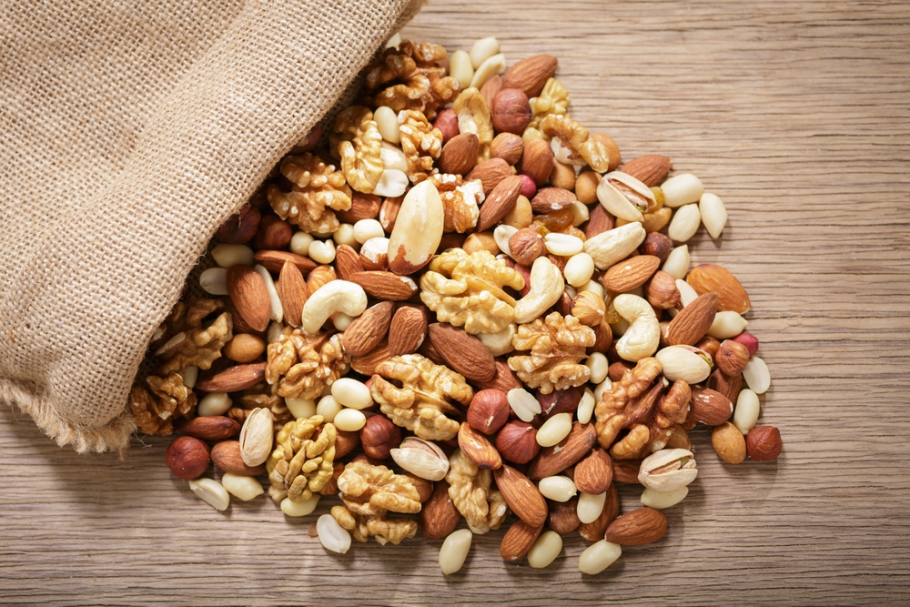 close up of sack of mixed nuts on wooden table, top view