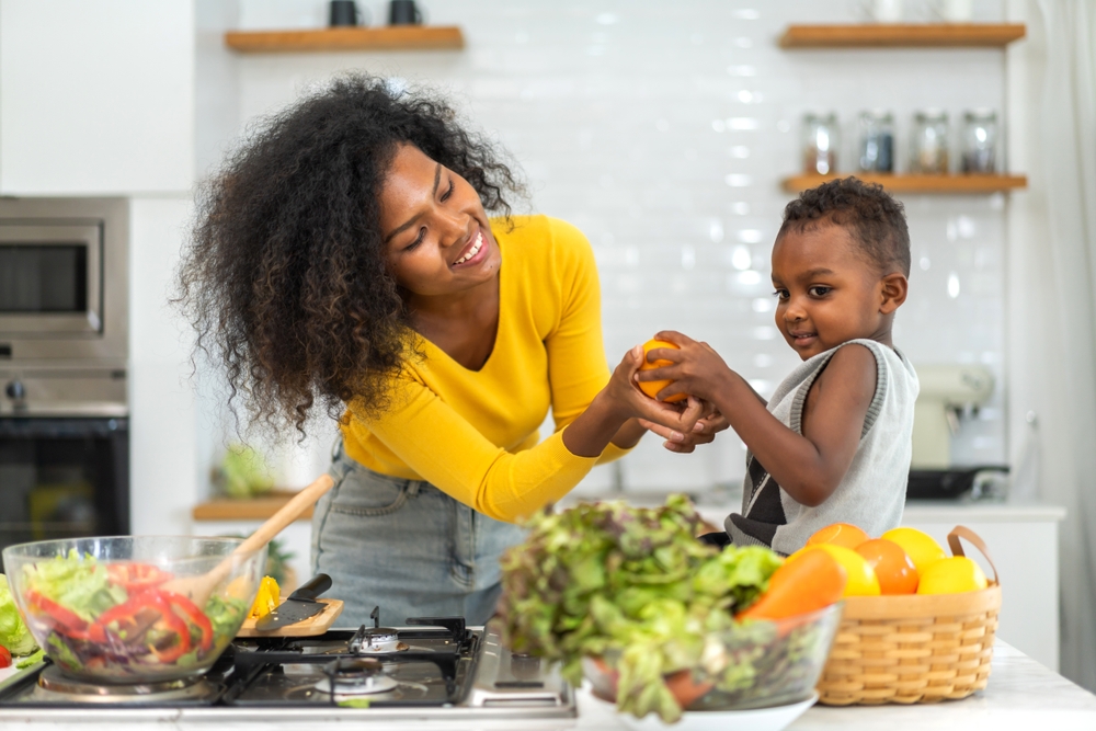 Portrait of enjoy happy love african american family mother and african little boy son child having fun help cooking food healthy eat together with fresh vegetable salad and ingredient in kitchen