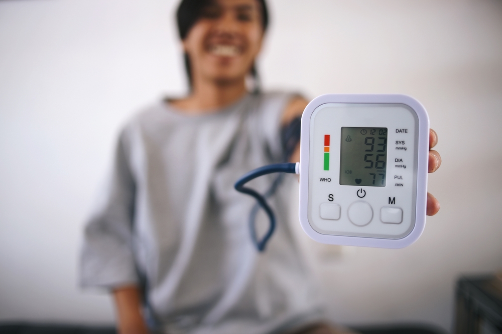 Happy Young Asian Man Medical Checking At Home Showing Blood Pressure Test