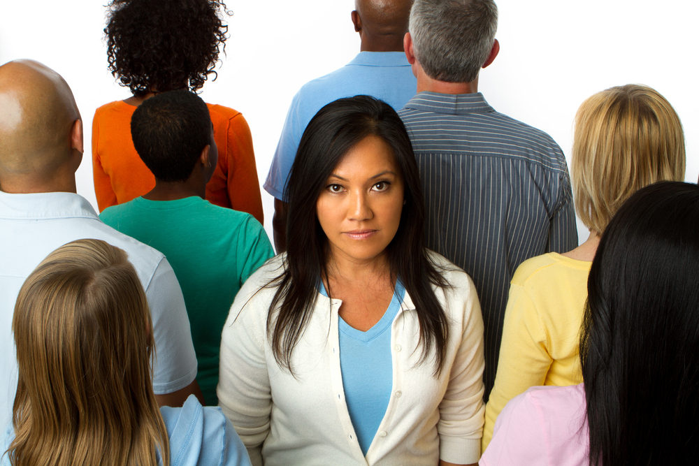 Asian woman standing alone in a crowd.