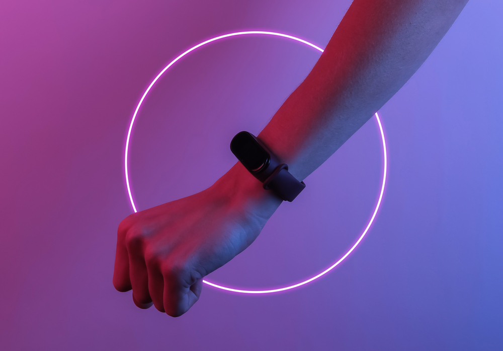 Female hand with a smart bracelet. Modern gadgets. Creative pop art pink blue neon color. Trendy gradient illumination. Night light
