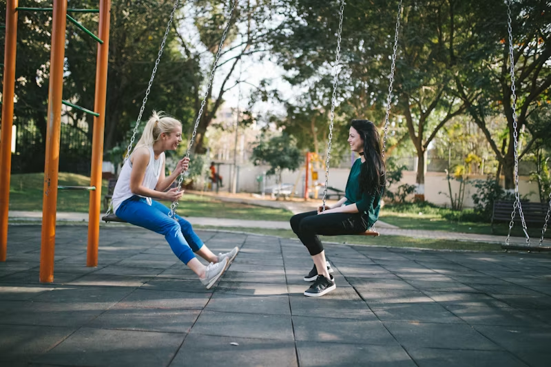 two women talking on a swingset