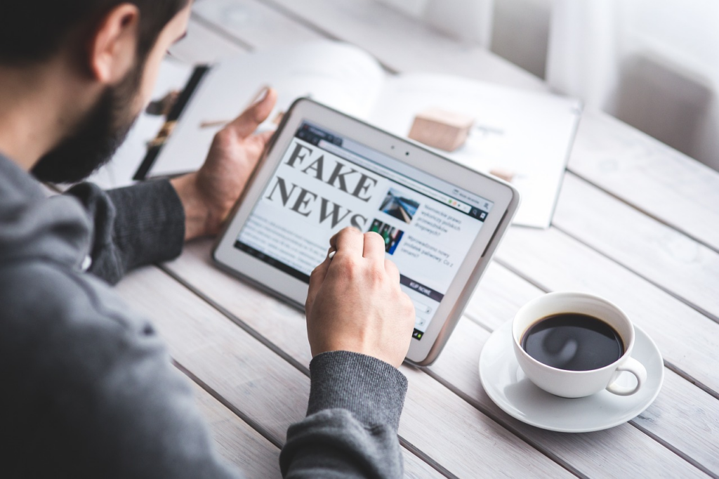 man reading a tablet that says "Fake News"