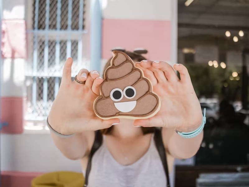 person holding up a poop emoji cookie