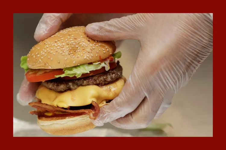 two gloved hands holding a burger