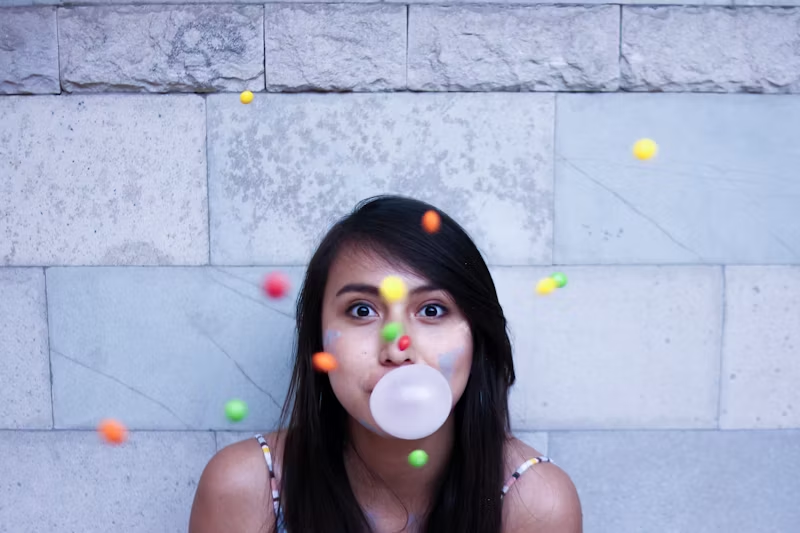 woman chewing gum with coloured candies in front of her