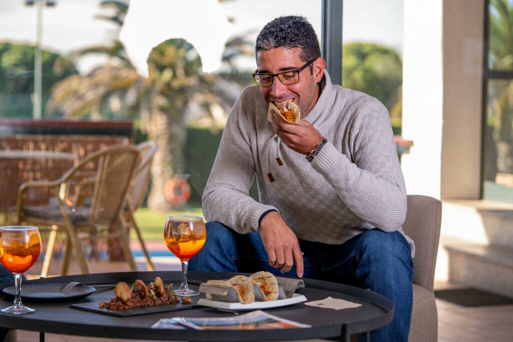 Man Enjoying Tacos and Drinks Indoors