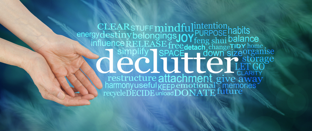 Angelic feather Declutter Word Cloud - female cupped hands offering the word DECLUTTER surrounded by a relevant tag word cloud on a dark blue green background with fine feathers