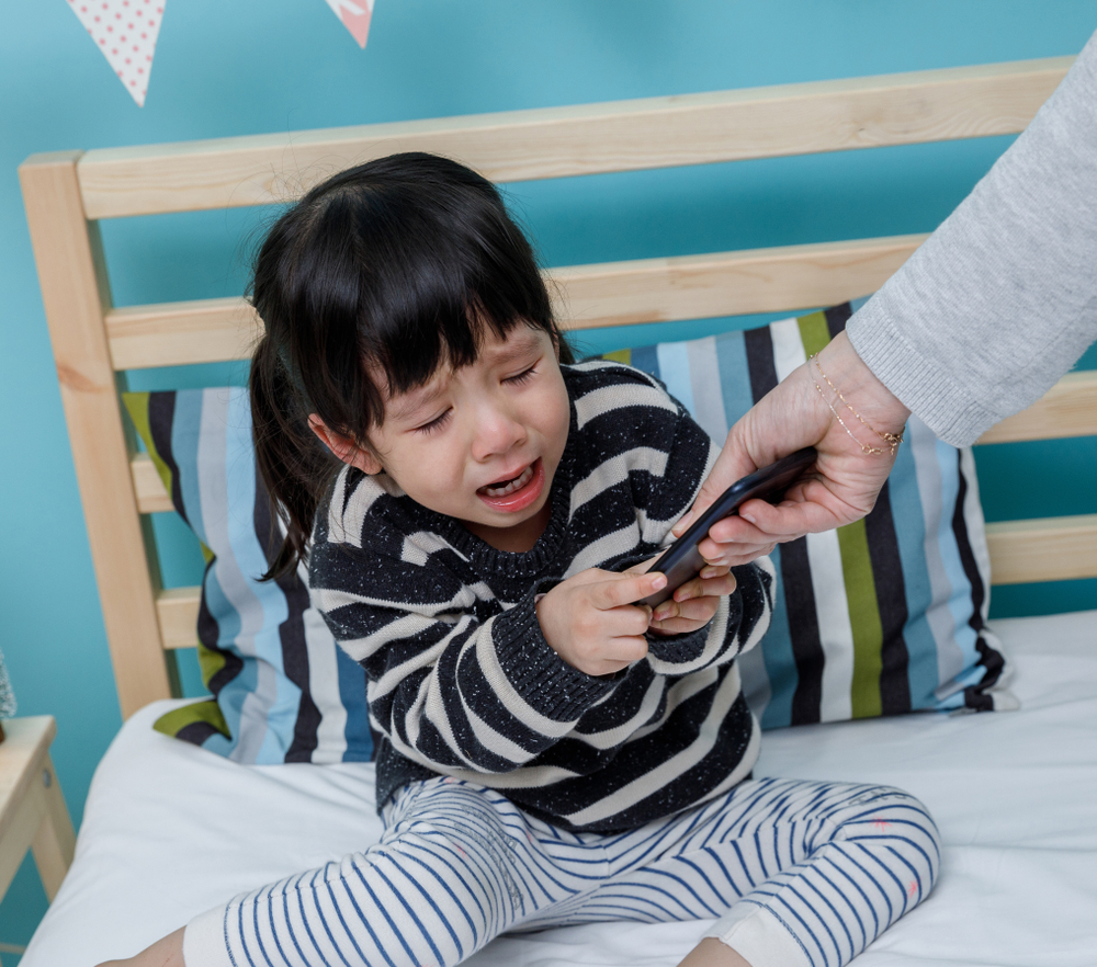 Her mother hold the phone with a crying child, Baby healthy and preschool concept
