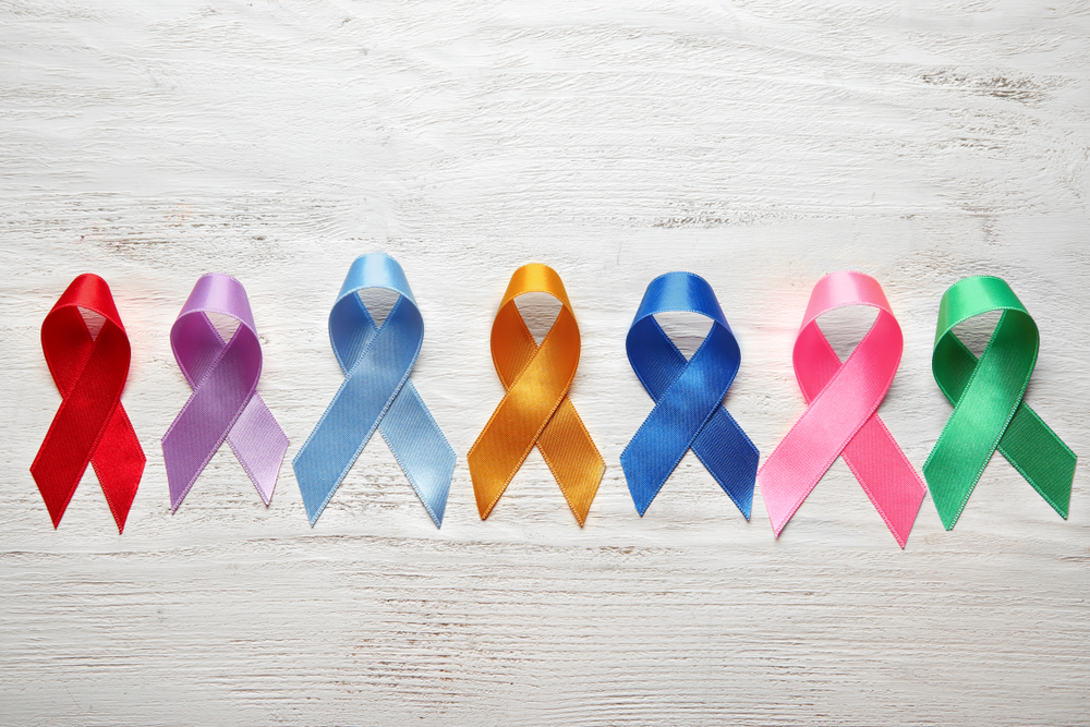 Different colorful ribbons on white wooden background. Cancer concept
