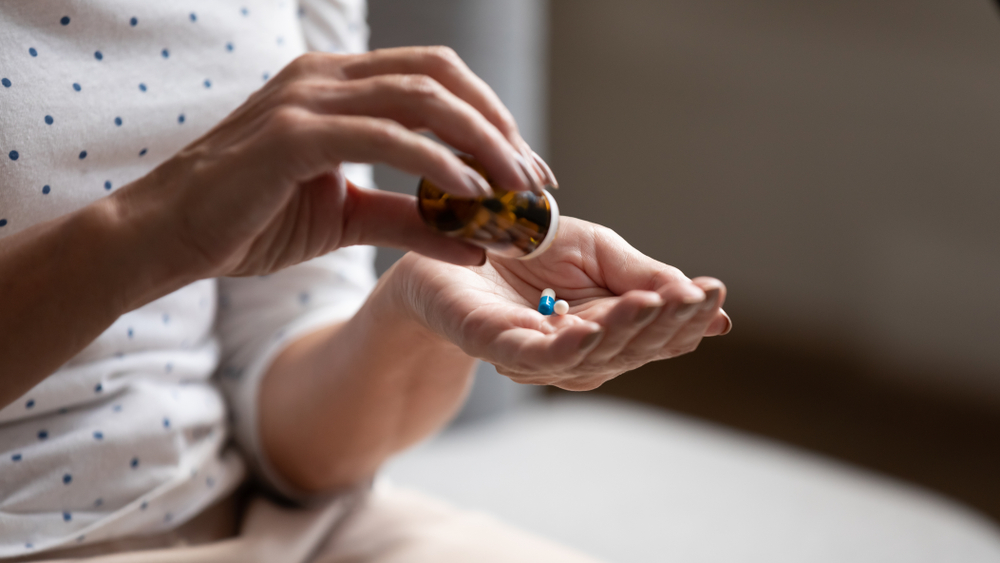 Close up 60s old woman pours out from bottle pills time to take medicaments, cure for memory loss, high blood pressure or cholesterol level remedy pain killer drugs, senile diseases treatments concept