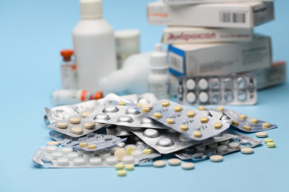 White blister pack of tablets pill statins for light resistance packaging on blue background. White and yellow tablets
