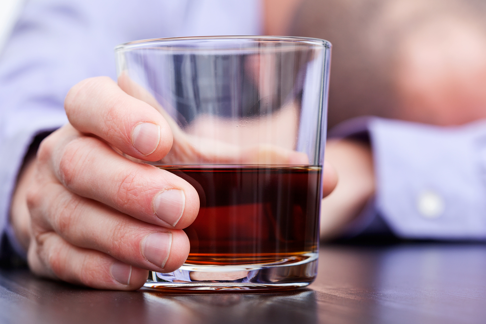 Glass with brandy and sleeping businessman in background
