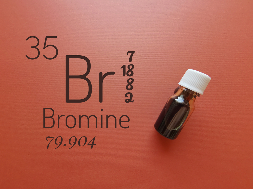 Bromine is a chemical element of the periodic table with the symbol Br and atomic number 35. The symbol Br with atomic data and reddish-brown liquid bromine solution in the background.