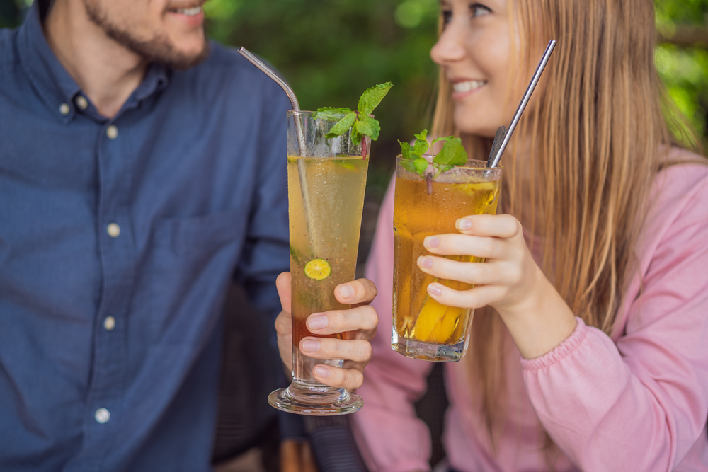 Eco friendly couple using reusable stainless steel straw to drink fruit tea