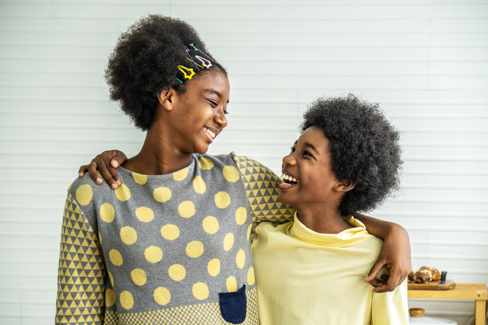 Happy Kids.Two cute adorable siblings african american children hug the neck and smile, Older sister hugs little brother by the neck