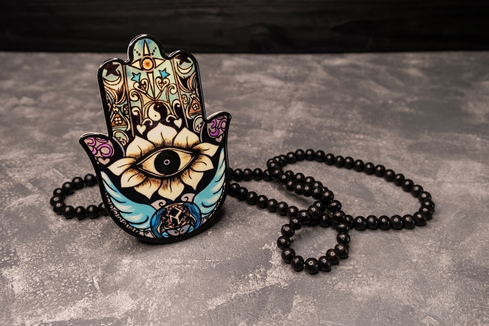 Decoration piece of a palm with an eye in it, called Hamsa hand. Hamsa hand amulet, used to ward off the evil eye - ceramic decoration. Hand of Fatima or Hand of Mariam in the form of a souvenir plate
