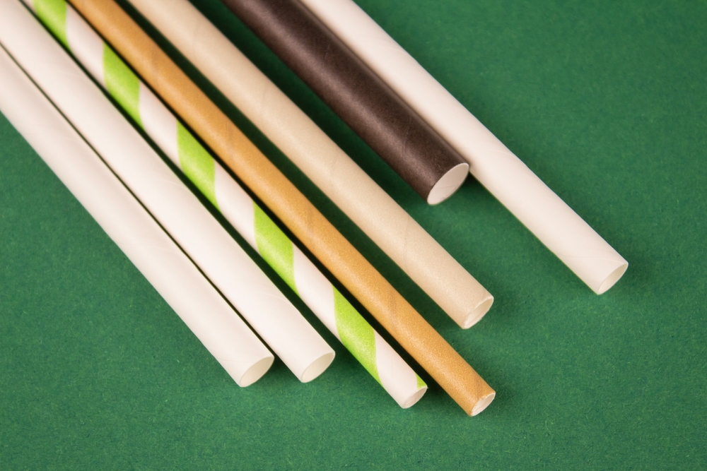 Set of different drinking paper straws on green background. Biodegradable drinking straws. Sustainable lifestyle and zero waste concept