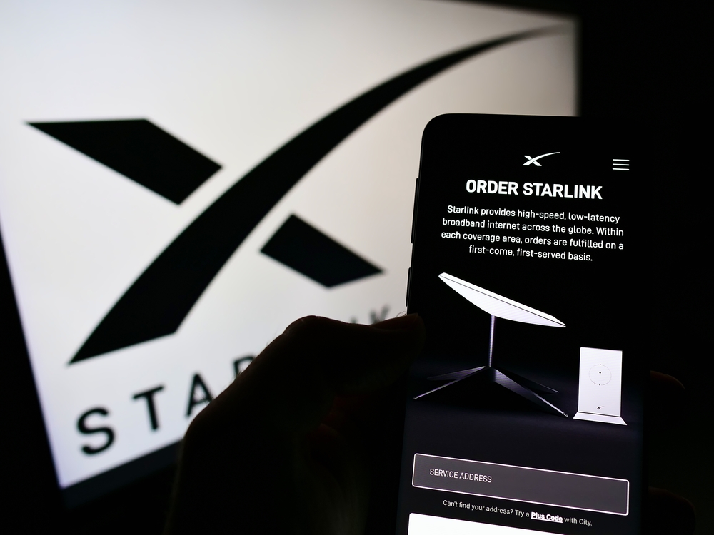 STUTTGART, GERMANY - Dec 05, 2021: Person holding cellphone with webpage of satellite Internet company Starlink (SpaceX) on screen in front of logo Focus on center of phone display
