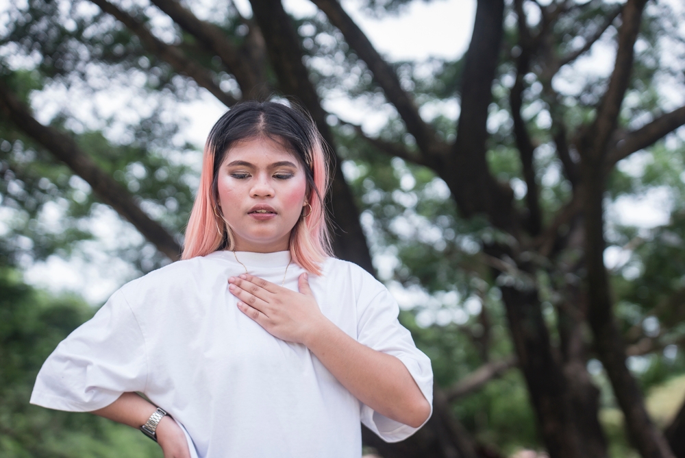 A young asian woman feels rapid, fluttering heartbeat on her chest. Possible cardiac problems, dyspnea or anxiety attack.