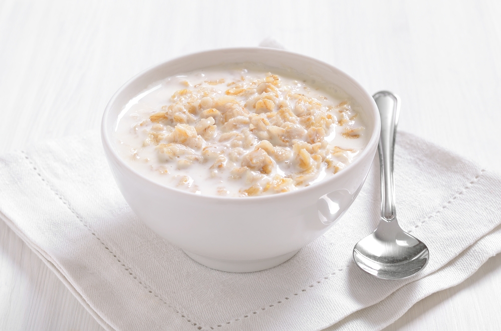 Oatmeal porridge in white bowl, close up view.