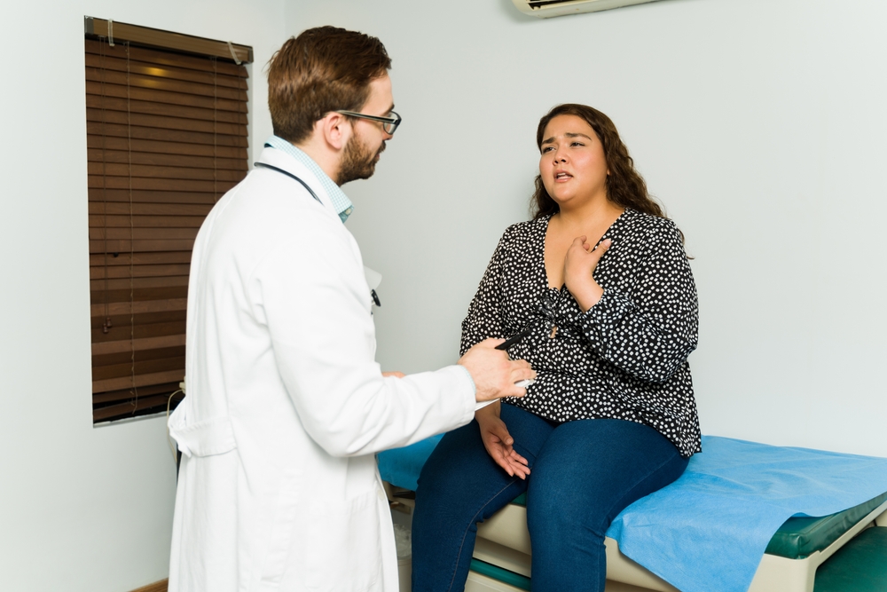 Worried hispanic woman speaking about her breathing problems and chest pain to her doctor during a medical examination