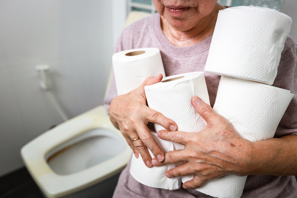 Senior woman carrying holding a lot of toilet paper in bathroom,many rolls of toilet paper for wiping,cleaning after urination or defecation,frequent urination problems or diarrhea in the old elderly
