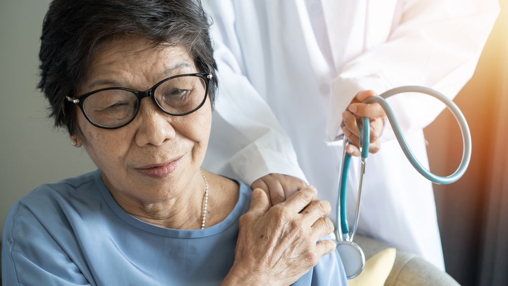 Elderly care with Asian old adult senior citizen woman patient holding geriatric doctor, caregiving nurse or family assistant's hand in hospice home for medical or mental therapy
