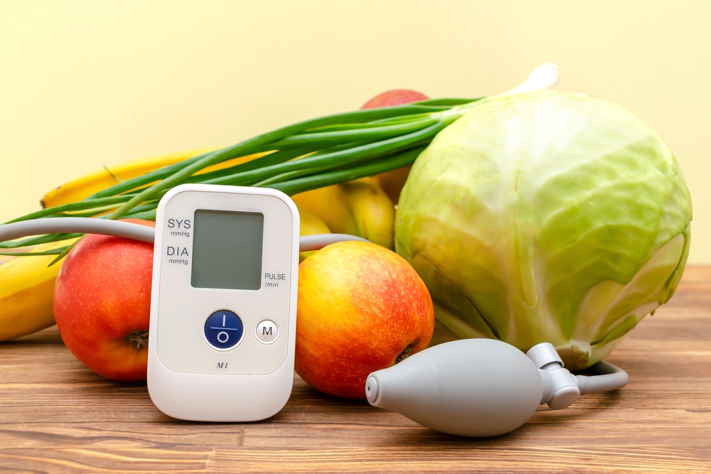 Tonometer and glucose meter,bunch of fresh vegetables,fruits, proper nutrition, healthy lifestyle, lowering blood sugar, heart pressure, diabetes concept on yellow,wooden background.