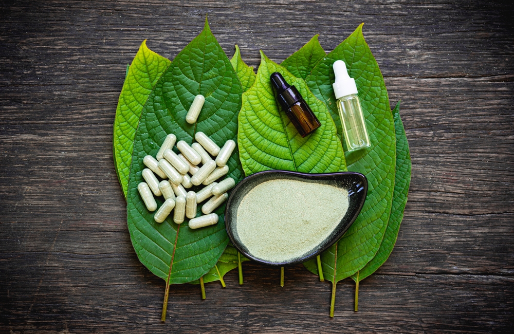 capsule of kratom leaf (Mitragyna speciosa) Mitragynine on wooden with powder . Drugs and Narcotics, kratom leave, kratom used in tradisional medicine , top view, oil extracts in jars