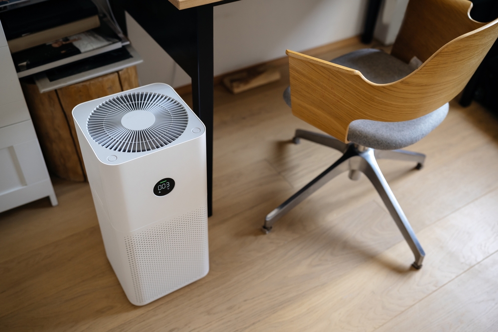 air purifier in the interior next to the workplace and armchair, cleaning from fine dust in the house. protect the concept of PM 2.5 dust and air pollution
