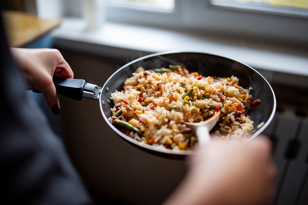 cooking tasty rice and vegetable mix with corn, pea, beans in pan on kitchen

