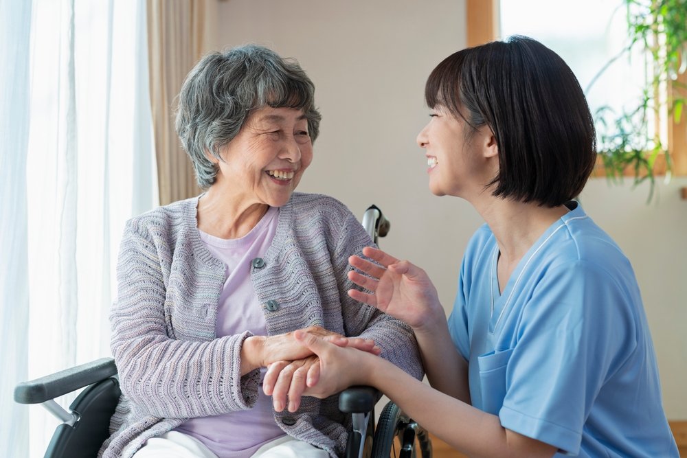 Senior woman in wheelchair indoors with Female Healthcare Professional
