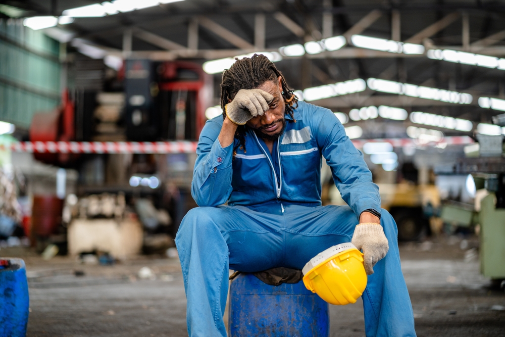 African American male technician feel tired from hard work in a repaired mechanic workshop manufacture, weak, hopeless, burned out, hot, fired unemployed feeling stressed.