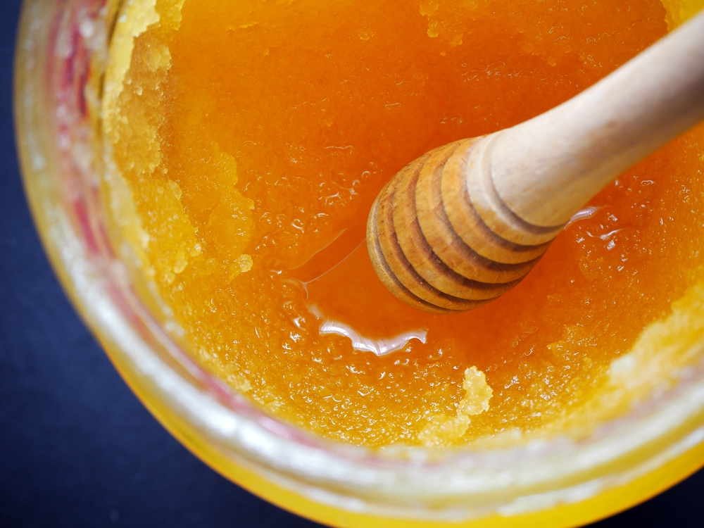 Caramelized honey dripping from a wooden spoon.