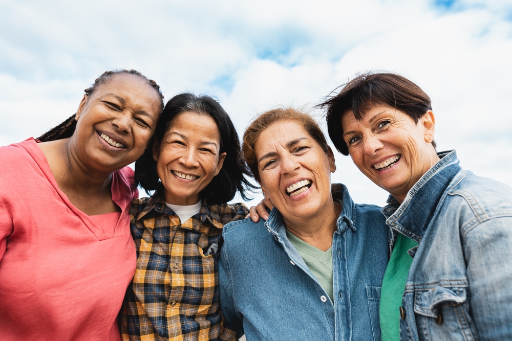 Happy multiracial senior women having fun smiling into the camera at house rooftop
