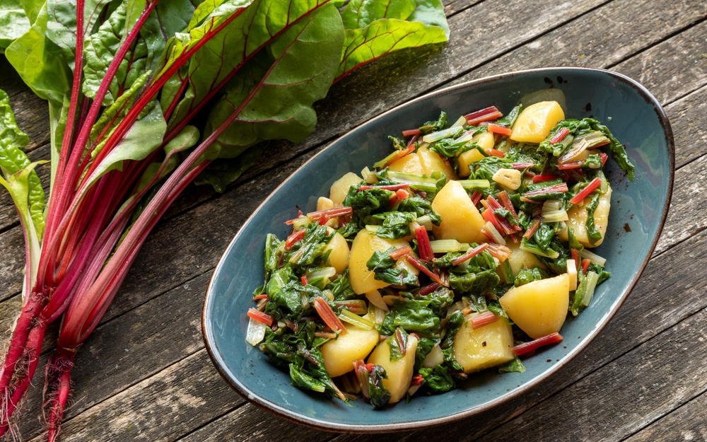 Blitva dish made with boiled potatoes, Swiss chard, garlic and olive oil. Fresh beet leaves on wooden rustic table.