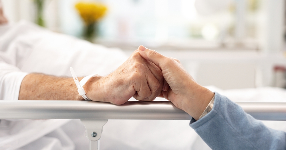 Hospital bed, support and senior couple holding hands, trust or comfort sick partner with healthcare problem. Bedroom, marriage love or elderly people care for mental health patient with medical risk
