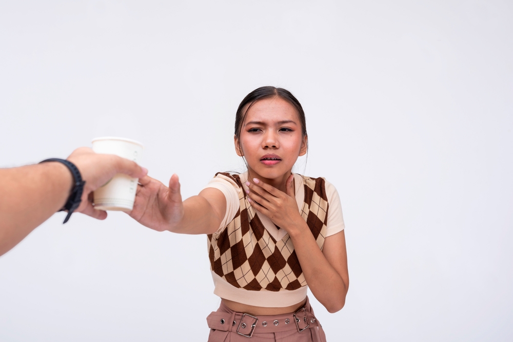 A thirsty asian woman desperately reaches out to someone holding a cup of water. A lady pleading for a drink. Isolated on a white background.