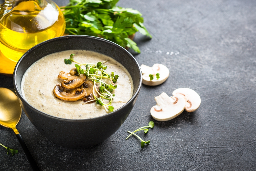 Mushroom Soup in craft bowl on dark stone table.