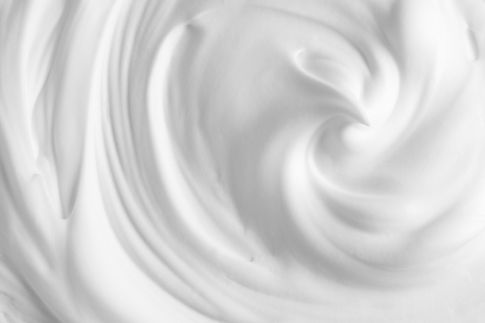 Thick foam swirl texture. White cream, mousse, cleanser, shampoo, shaving foam. Foamy cosmetic product closeup