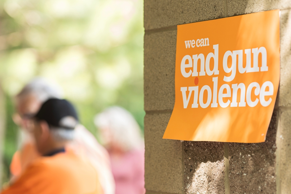 A sign reading "We can end gun violence" marks the site for people to gather for a local gun violence awareness meeting.
