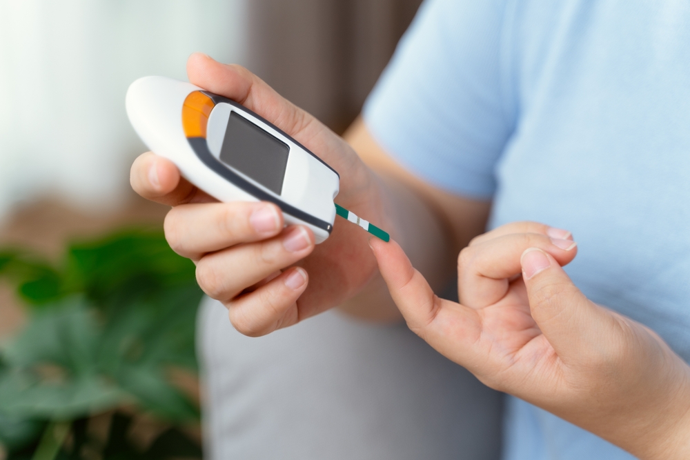 Asian woman using lancet on finger for checking blood sugar level by Glucose meter, Healthcare and Medical, diabetes, glycemia concept
