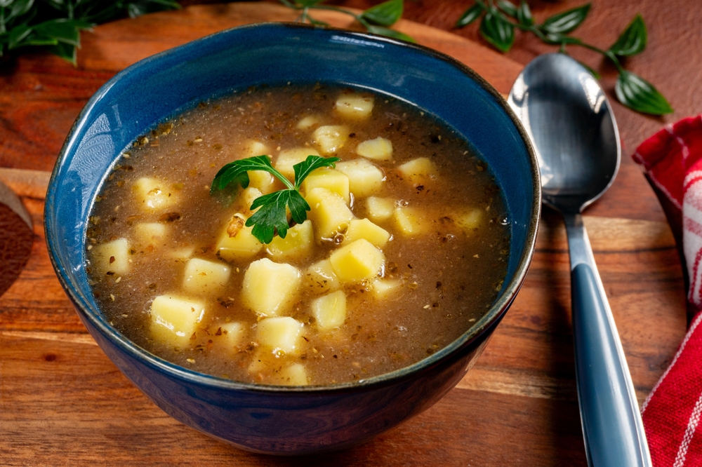 Sour soup with mushroom served with potatoes in blue bowl.