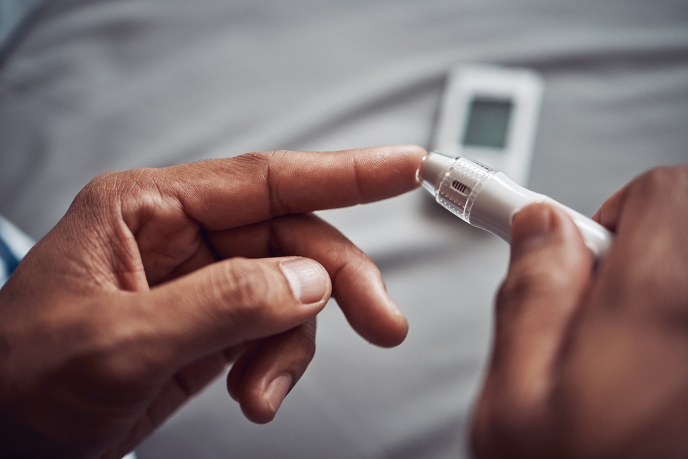 Person, hand and blood sugar with finger for diabetes test or monitor insulin, glucometer or home. Medical, pen and checking as healthy measure or genetic problem with wellness, diagnostic or device
