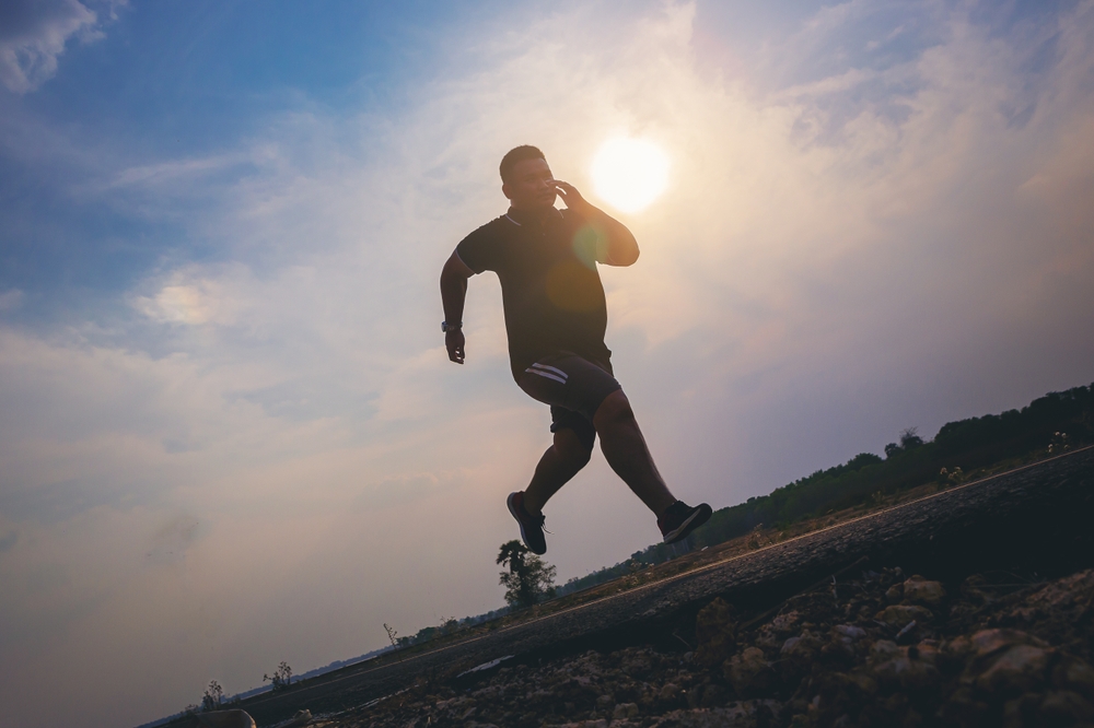 Silhouette of overweight man running sprinting on road. Fat man runner jogging at outdoor workout. Exercise concept for weight control.