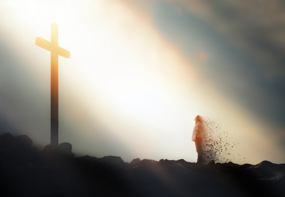 Christian standing in front of the cross of Jesus Christ with bright light shining on it, concept of faith and belief, grace and rebirth by the Holy Spirit