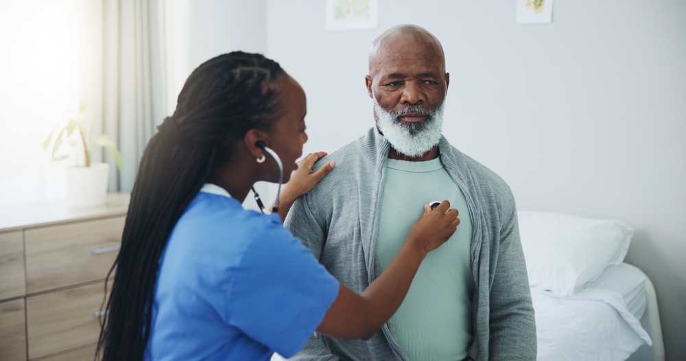 Senior, man and nurse with listening on stethoscope for heartbeat assessment or cardiovascular health on bed. Elderly patient, doctor and cardiology in hospital for lung disease or chest infection
